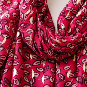 Macro shot of rose red linen feel scarf featuring elegant gold foil leaf pattern detail