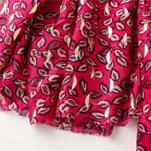 Detail of fuchsia cotton linen scarf with golden leaf patterns and soft fringe edges