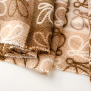 Detail of soft cashmere feel scarf with vintage anagram jacquard pattern and fringe edge