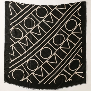 Detail of black cotton-linen scarf with geometric letter patterns and fringe edges