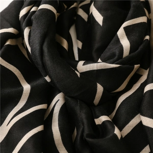 Detail shot of soft cotton linen scarf showing black fabric with cream abstract patterns