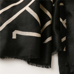 Detail of black cotton linen scarf with beige geometric patterns and fringe edges