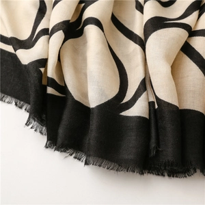 Close-up of abstract geometric patterns and delicate fringe on a soft cotton linen shawl