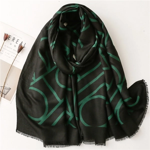 Soft cotton-linen feel scarf with green geometric letters and tassel edges on white background