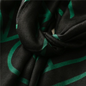 Detail of woven shawl showing soft cotton texture and green geometric lines on black fabric