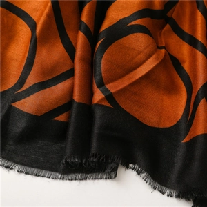 Detailed close-up of geometric orange and black scarf with soft frayed fringe edges