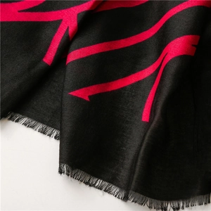 Close-up of soft black scarf with pink arrow patterns and delicate fringed edges