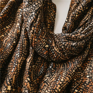 Détail d'une écharpe léopard douce avec texture dorée métallisée et tissu tissé fin