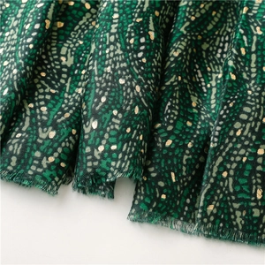 Détail de l'écharpe verte avec textures abstraites, dorures et bordures à franges