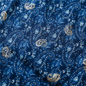 Macro detail of navy blue scarf fabric with gold paisley patterns and woven texture