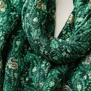 Close-up of green paisley scarf with golden foil printing and soft cotton-linen texture