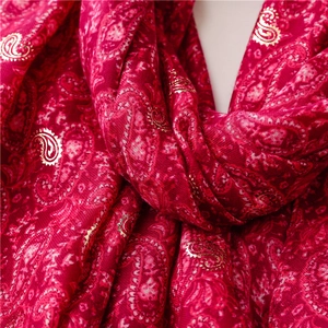 Detailed macro view of vintage paisley pattern with golden foil on thick red scarf