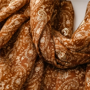 Detail of paisley pattern with gold foil print on a ginger soft cotton-linen shawl