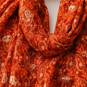 Detail of red paisley scarf showing rich fabric texture and gold foil patterns