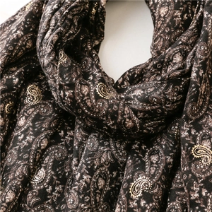 Macro detail of gold paisley patterns on thick vintage scarf showing fabric texture