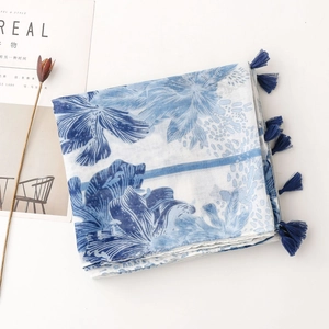 Detail of blue floral porcelain print cotton linen scarf with deep blue fringe tassels