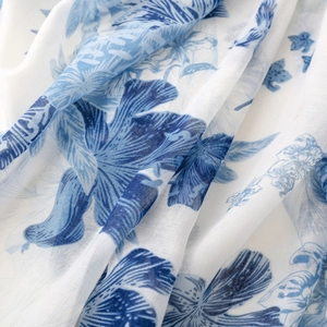 Detailed macro view of white linen fabric with blue ink-wash floral patterns and texture
