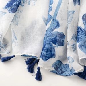 Close-up of blue floral print on lightweight white cotton linen scarf with tassels