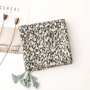 Detail of green leopard print cotton scarf with decorative tassels and fringe accents