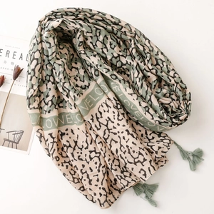 Detail of cotton linen feel scarf with leopard print texture and green tassel accents