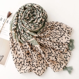 Detail of leopard print cotton linen scarf featuring dark green corner tassel accents
