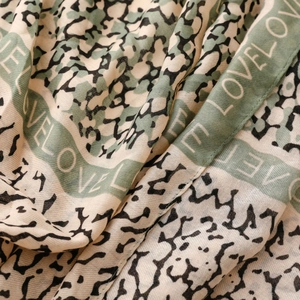 Detailed macro shot of leopard print scarf with sage green stripes and LOVE text detail
