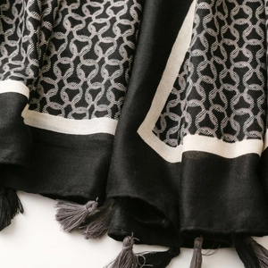 Close-up of black and grey scarf featuring geometric chain patterns and elegant tassel fringe