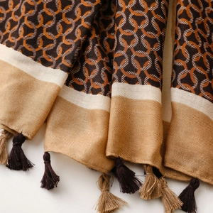 Detail of warm scarf with orange geometric rings, woven texture, and tassel fringe