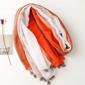 Sciarpa sfumata arancione con nappe presentata in un allestimento lifestyle in piano