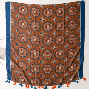 Vista dettagliata della sciarpa boho con motivi geometrici blu e nappe arancioni sui bordi