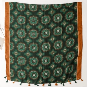 Dettaglio di scialle etnico verde bosco con motivi geometrici a stella e nappe