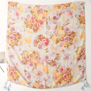 Detailed flat lay of floral scarf featuring vintage rose patterns and blue corner tassels