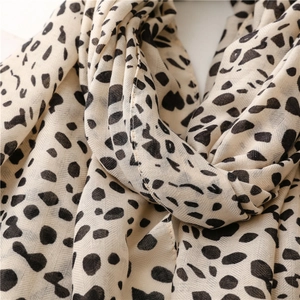 Detailed macro view of beige scarf featuring black dalmatian leopard print patterns
