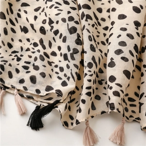 Close-up of beige leopard print scarf featuring woven texture and handmade tassels