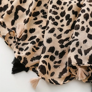 Macro shot of leopard print scarf fabric texture with decorative fringe tassels