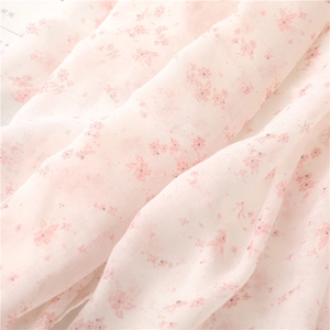 Close-up of lightweight light pink floral fabric with soft texture and tassels