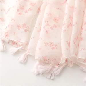 Detailed macro view of pink floral pattern on cotton linen scarf with white fringe tassels