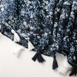 Macro shot of navy floral scarf showing cotton-linen texture and handcrafted tassels