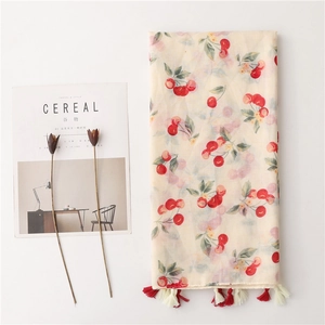 Chic cream-colored linen scarf with red cherry prints and tassels on white surface