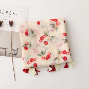 Detail view of cotton linen scarf with cherry print and decorative red tassels