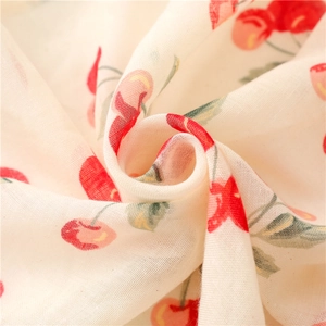 Detail of soft linen scarf fabric showing cute cherry prints and delicate texture