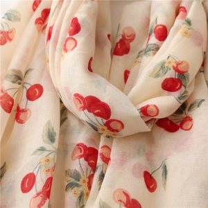 Close-up of lightweight cotton linen scarf showing red cherry prints and soft fabric texture
