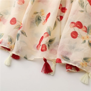 Detail of soft off-white cotton scarf with cherry prints and red white tassel edges