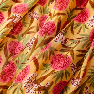 Detail of yellow cotton linen scarf featuring hand-painted pink floral patterns and soft texture