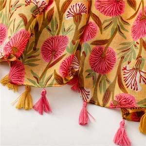Close-up of a floral cotton linen scarf with soft texture and pink tassel trim detail