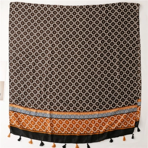 Detail of dark brown scarf with white geometric circles and colorful ethnic fringe borders