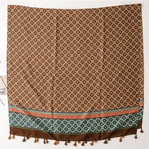 Macro shot of ethnic pattern scarf featuring vintage bronze prints and red tassel fringe