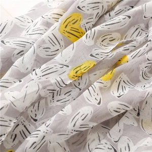 Detail of light gray cotton linen scarf featuring yellow and white heart print texture
