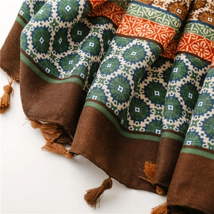 Detail of ethnic floral print scarf with intricate patterns and long brown tassels