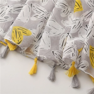 Detail of soft linen scarf featuring hand-painted leaf patterns and decorative tassels